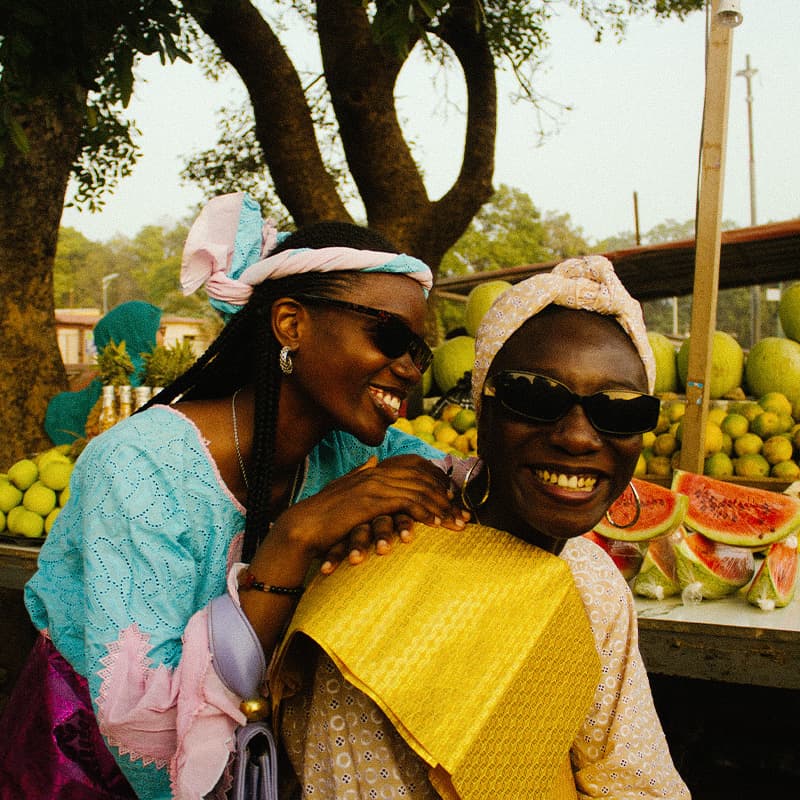 Two women smiling at a fruit stall