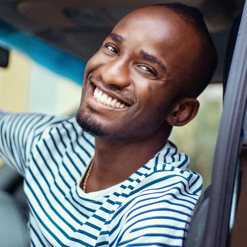 A smiling man leaning out of a car window