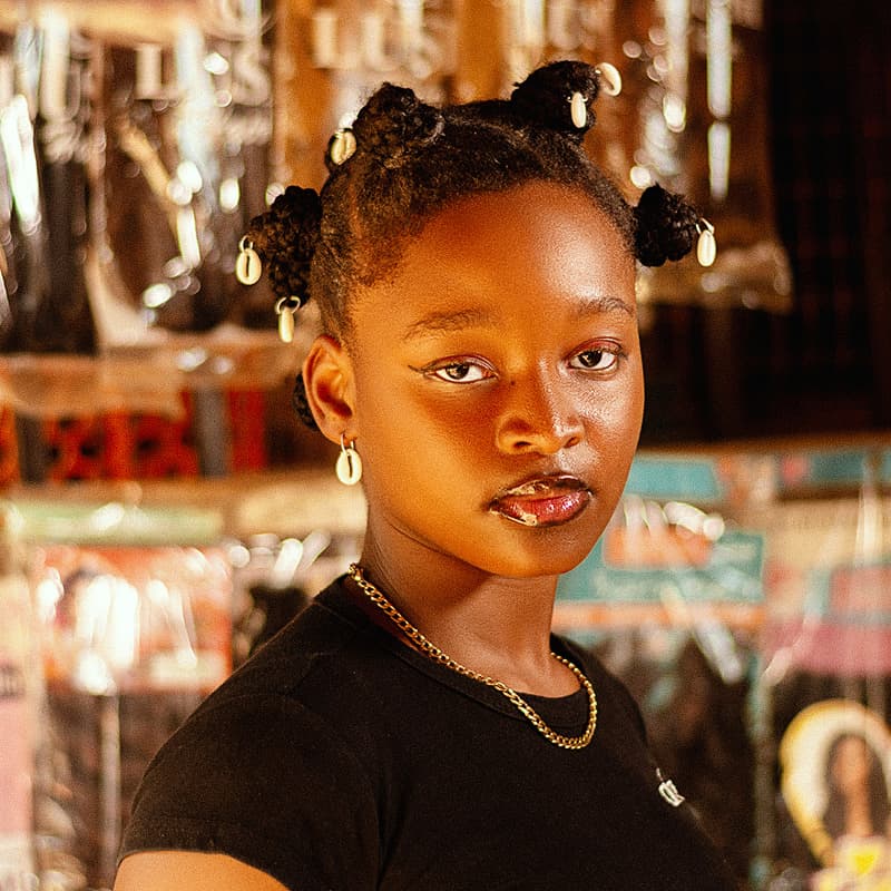 A young woman in a shop with hair products behind her
