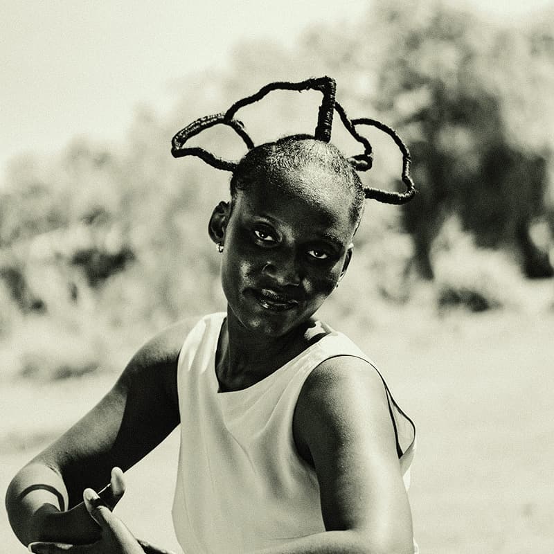A black-and-white portrait of a young woman outdoors