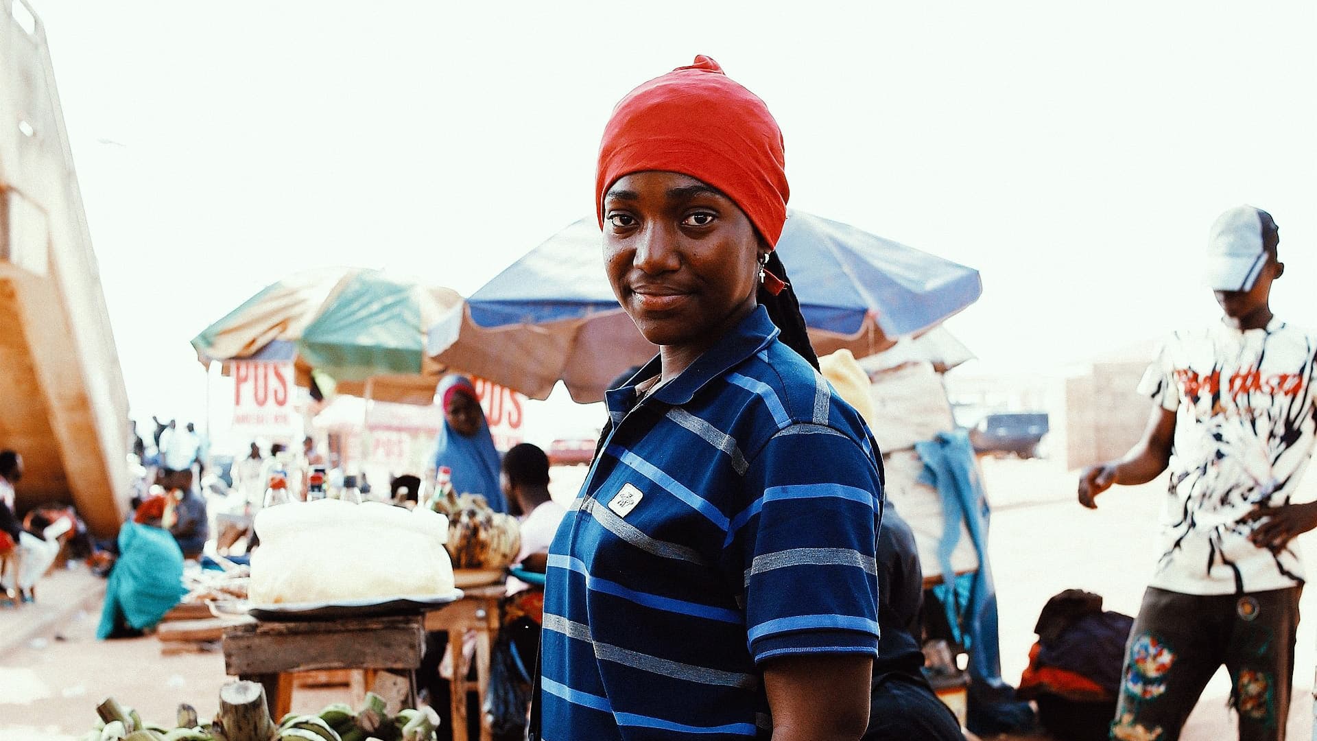 A woman in a red cap at an outdoor market